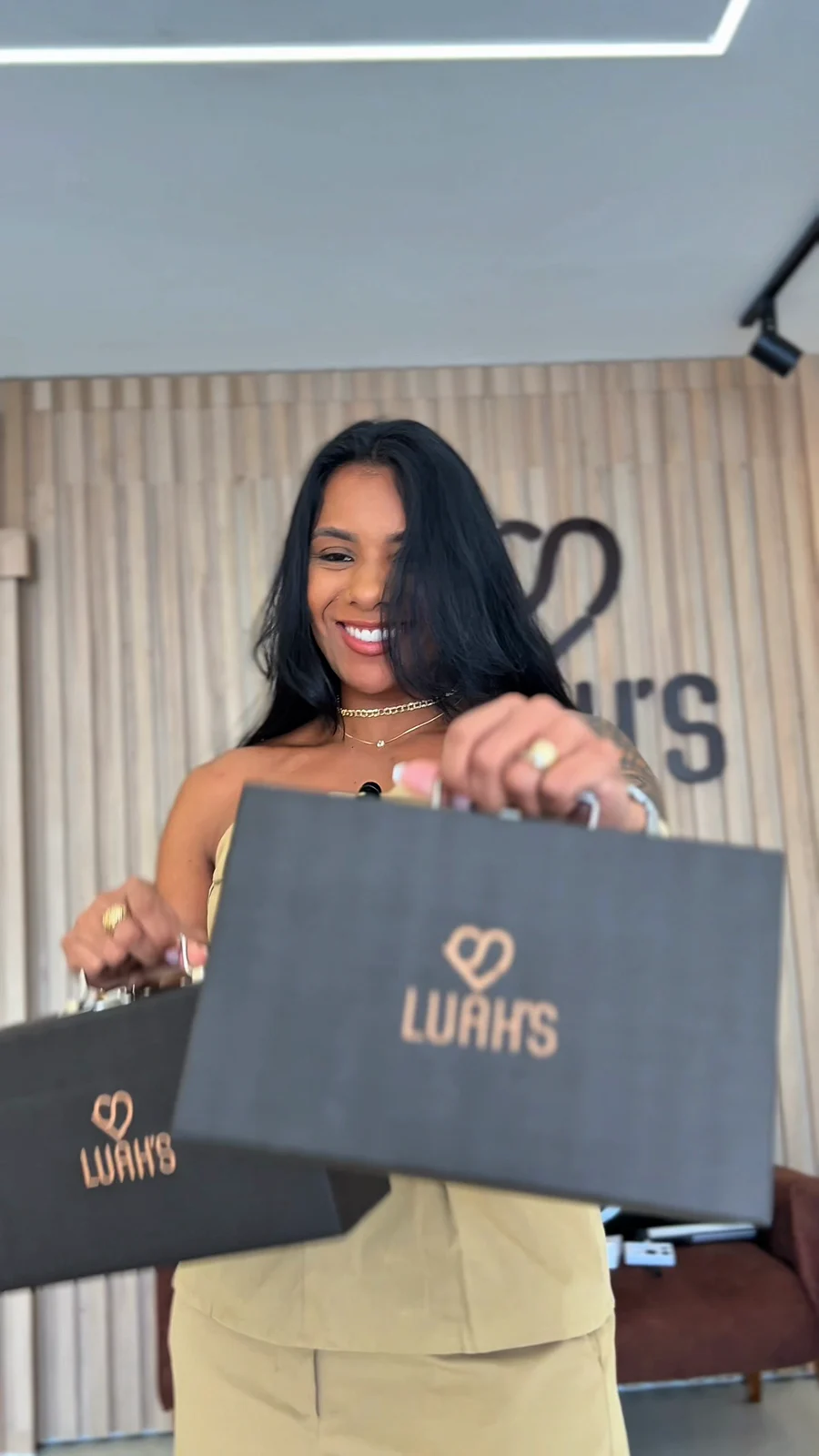 Mulher com duas sacolas Luah’s diante da marca na loja